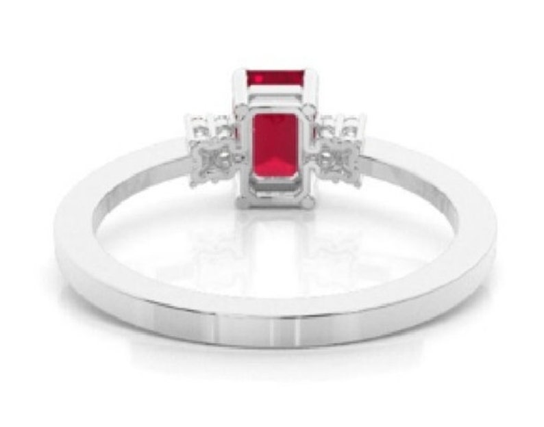 Pu&ograve; includere: Un anello d'argento con una vibrante gemma rossa rettangolare come punto focale. L'anello &egrave; impreziosito da gemme chiare pi&ugrave; piccole su entrambi i lati della pietra principale, incastonate su una fascia lucida ed elegante.