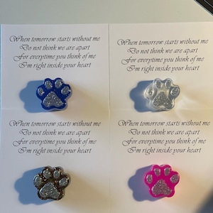 Puede incluir: Cuatro dijes de resina en forma de huella de pata con purpurina. Cada dije tiene un color diferente: azul, blanco, marrón y rosa. Los dijes están unidos a tarjetas con un poema que dice: "Cuando mañana empiece sin mí, No pienses que estamos separados, Porque cada vez que pienses en mí, Estoy en lo profundo de tu corazón."