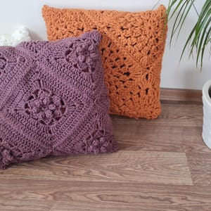May include: Three crocheted throw pillows in different colors and patterns. The pillows are white, purple, and orange. They are arranged on a wooden floor.
