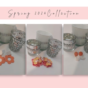 May include: Three sets of earrings, one set is orange flower shaped, one set is white and orange, and the last set is a white flower with a brown centre. The earrings are displayed on a white surface with silver candle holders.
