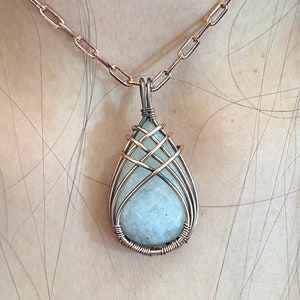 May include: A copper wire wrapped pendant necklace featuring a light blue teardrop-shaped gemstone.