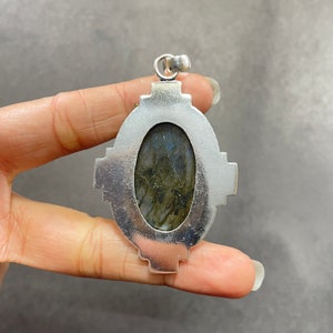 Puede incluir: Pendiente de plata con una gran piedra ovalada de labradorita engastada en un marco de plata detallado.
