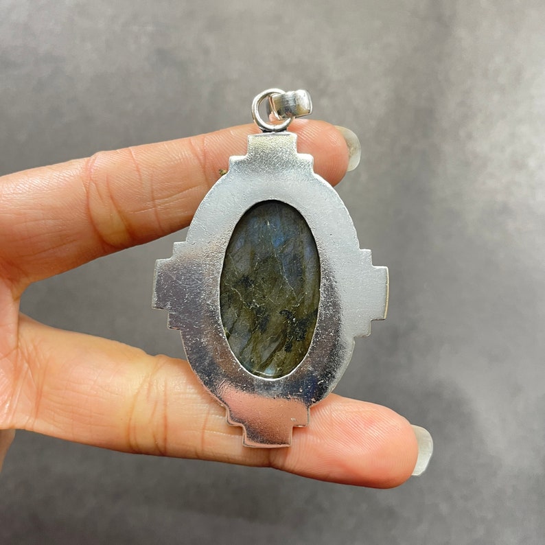 Puede incluir: Pendiente de plata con una gran piedra ovalada de labradorita engastada en un marco de plata detallado.