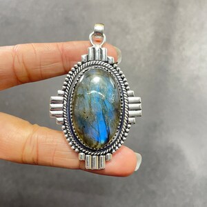 Puede incluir: Pendiente de plata con una gran piedra ovalada de labradorita. El pendiente tiene un dise&ntilde;o de plata detallado alrededor de la piedra.