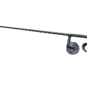 May include: A black metal handrail with a twisted design and a decorative scroll at the end. The handrail is mounted to a wall with a round metal plate.