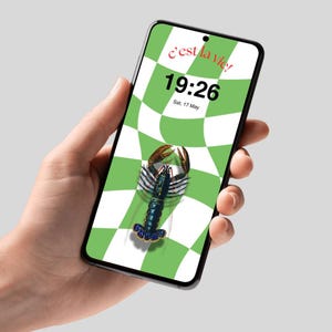 Può includere: Uno smartphone mostra uno sfondo a scacchi verdi e bianchi con un'illustrazione di aragosta. Lo schermo mostra l'ora 19:26 e la data sab, 17 maggio. La frase "c'est la vie!" è scritta in rosso in alto.