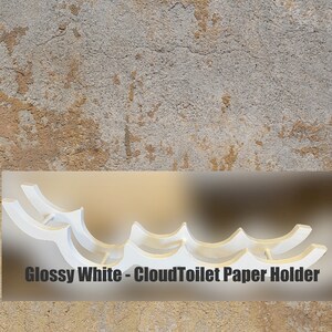 May include: Glossy white toilet paper holder with a wave-like design. The holder is made of plastic and has a modern look.