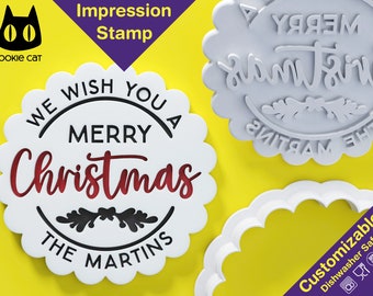 May include: White plastic Christmas cookie cutter with a scalloped edge. The cutter is shaped like a circle and has the text "We wish you a Merry Christmas The Martins" in black lettering. The word "Christmas" is in red lettering. The cutter is on a yellow background.