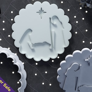 May include: White plastic cookie cutter with a scalloped edge, featuring a nativity scene with Mary, Joseph, and the baby Jesus. The cutter also includes a star above the scene. Dishwasher safe.