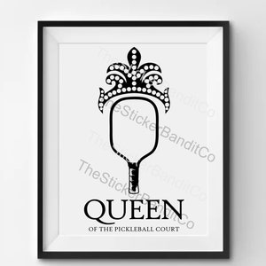 May include: Black and white illustration of a pickleball paddle with a crown on top. The text "QUEEN OF THE PICKLEBALL COURT" is below the paddle.