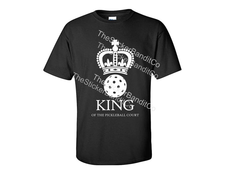 May include: Black t-shirt with a white design of a crown, a pickleball, and the text "KING OF THE PICKLEBALL COURT".