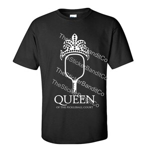 May include: Black t-shirt with a white graphic of a pickleball paddle with a crown on top. The text "Queen of the Pickleball Court" is below the graphic.