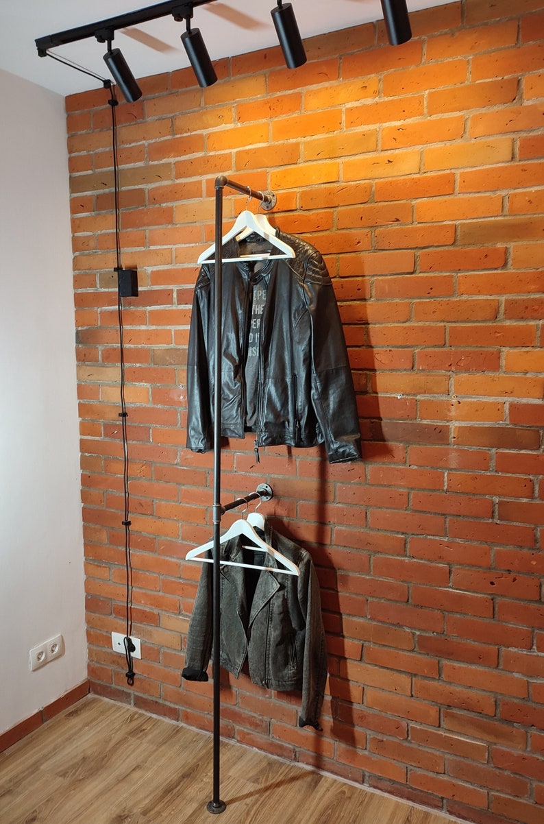 Industrial wall mounted clothes rack made of a steel pipe and joints, screwed to a red brick wall. It has two hangers of the selected length. Hanging jackets display / looks very nicely.