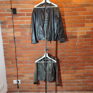 Industrial wall mounted clothes rack made of a steel pipe and joints, screwed to a red brick wall. It has two hangers of the selected length. Hanging jackets display very nicely.