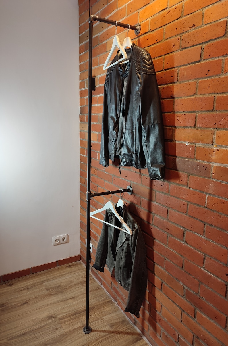 Industrial wall mounted clothes rack made of a steel pipe and joints, screwed to a red brick wall. It has two hangers of the selected length. Hanging jackets display / looks very nicely.