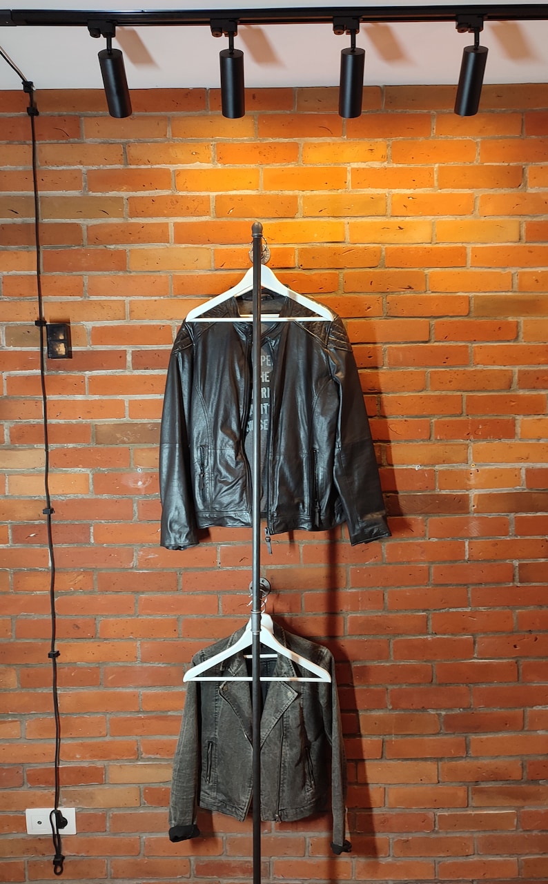 Industrial wall mounted clothes rack made of a steel pipe and joints, screwed to a red brick wall. It has two hangers of the selected length. Hanging jackets display very nicely.