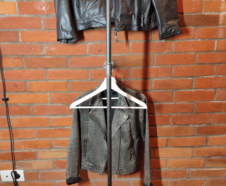 Industrial wall mounted clothes rack made of a steel pipe and joints, screwed to a red brick wall. It has two hangers of the selected length. Hanging jackets display very nicely.