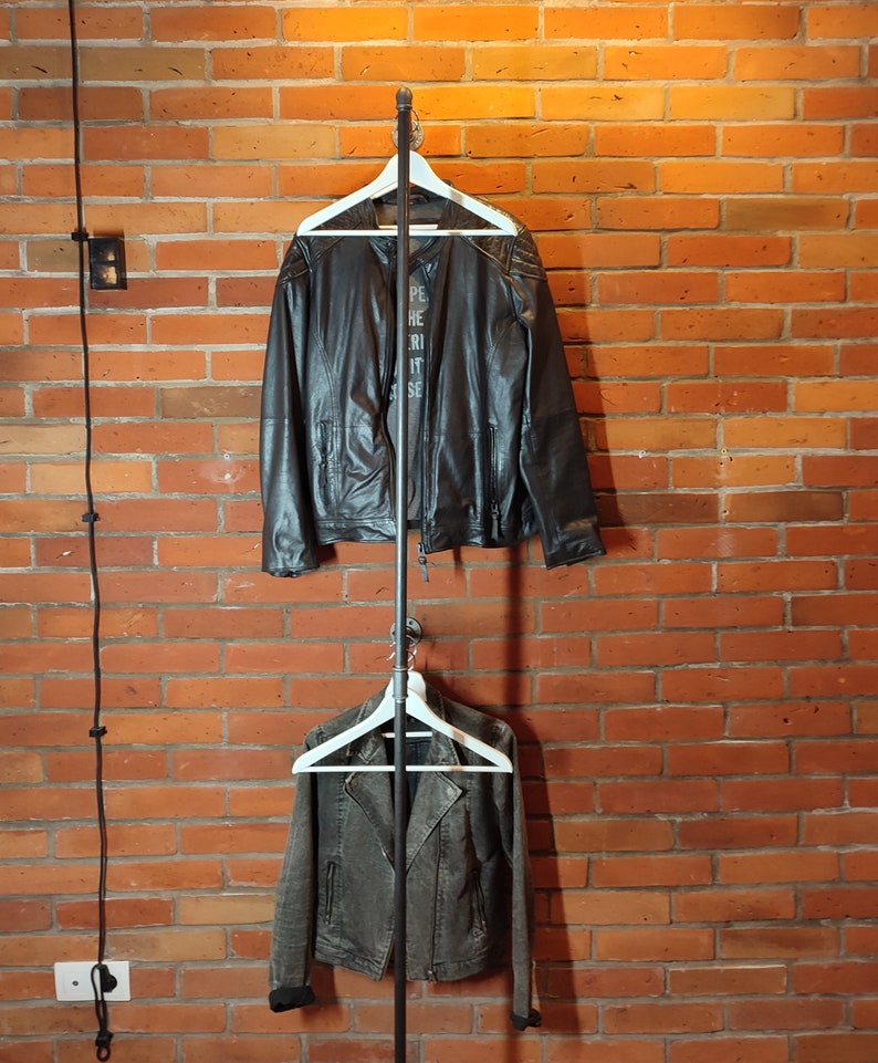 Industrial wall mounted clothes rack made of a steel pipe and joints, screwed to a red brick wall. It has two hangers of the selected length. Hanging jackets display very nicely.