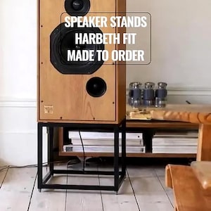 Puede incluir: Una taza de cerámica blanca con asa negra y el texto "But First, Coffee" en negrita negra. La taza se encuentra sobre un fondo borroso, sugiriendo un ambiente acogedor.