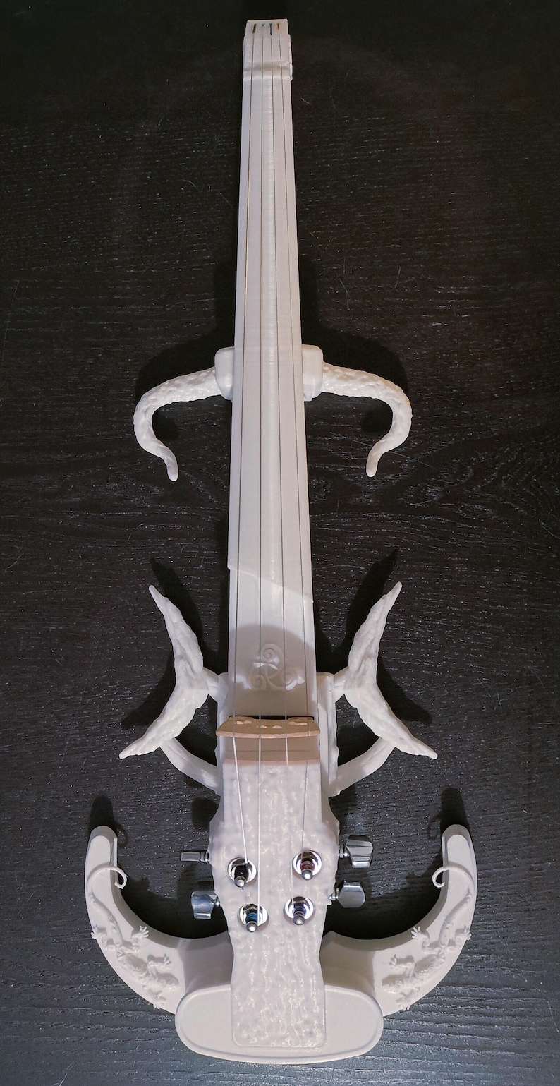 Puede incluir: Viol&iacute;n el&eacute;ctrico blanco impreso en 3D con un dise&ntilde;o &uacute;nico que presenta figuras de lagarto en el cuerpo y el clavijero. El viol&iacute;n tiene cuatro cuerdas y una superficie texturizada.