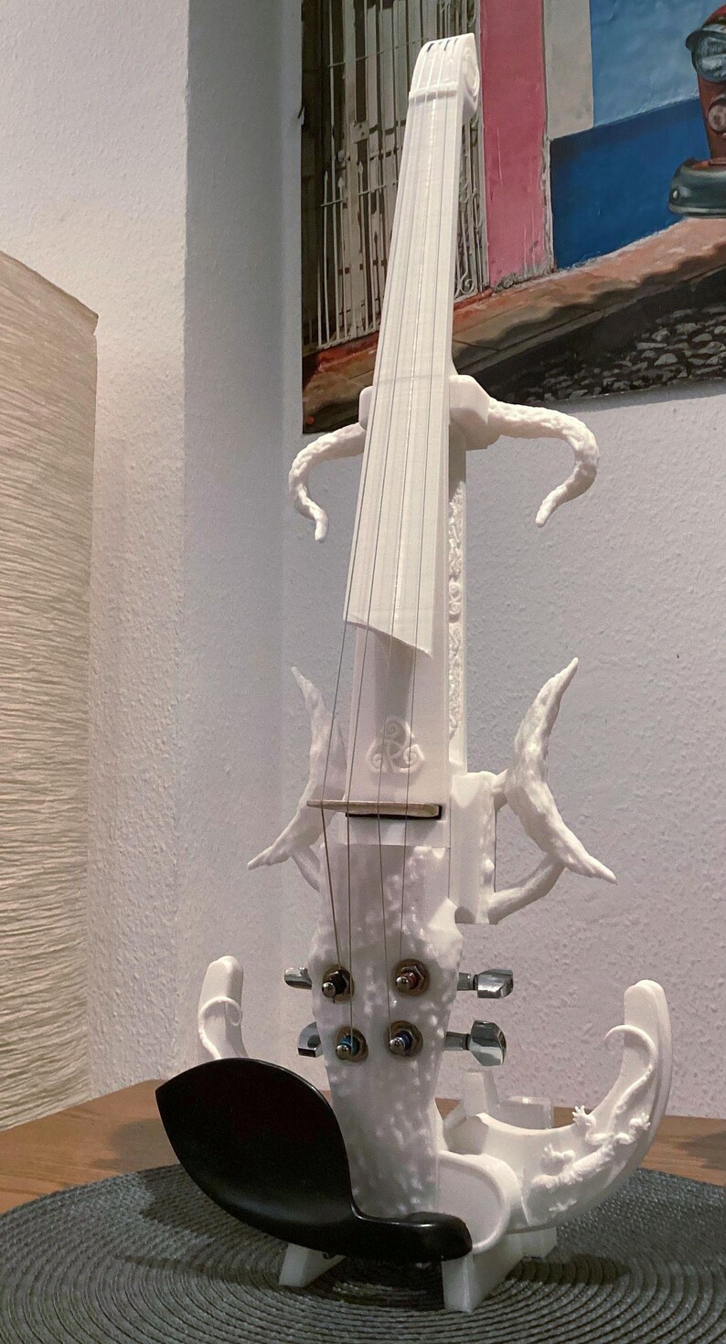Puede incluir: Un viol&iacute;n el&eacute;ctrico blanco con un dise&ntilde;o org&aacute;nico &uacute;nico. El viol&iacute;n tiene un cuerpo tallado y texturizado y un reposacabezas negro.