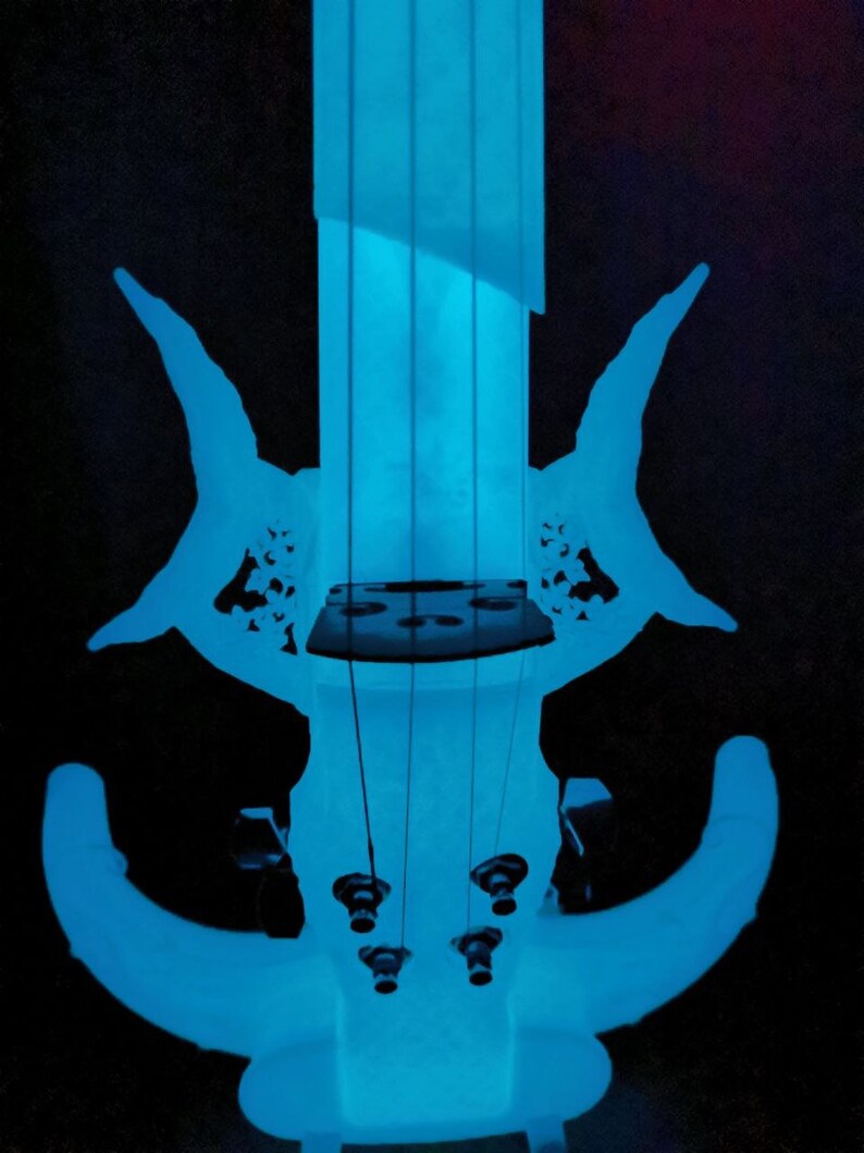 May include: A blue electric violin with a unique design. The violin has a futuristic look with a curved body and a long neck. The strings are visible and the tuning pegs are at the top of the neck.