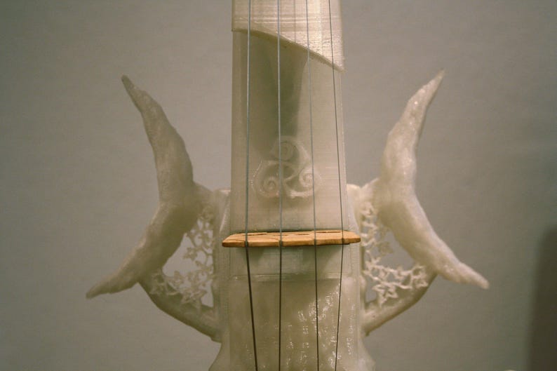 May include: A white 3D printed violin with intricate details and a wooden bridge. The violin has a unique design with two wing-like structures on either side of the neck.