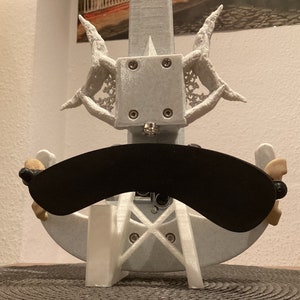 K&ouml;nnte beinhalten: Ein wei&szlig;er 3D-gedruckter Geigenst&auml;nder mit einem schwarzen, gebogenen Schalld&auml;mpfer. Der St&auml;nder hat ein dekoratives Design mit filigranen Details.