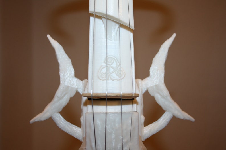 Puede incluir: Viol&iacute;n blanco impreso en 3D con detalles intrincados y un dise&ntilde;o de nudo celta en el cuello. El viol&iacute;n tiene dos alas curvas a cada lado del cuello.