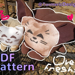 Pode incluir: Dois brinquedos de pelúcia em forma de gato, um marrom e outro branco, com rostos bordados e corações desenhados ao redor deles. O texto "PDF Pattern" e "Oven Fresh!" está escrito abaixo dos brinquedos.
