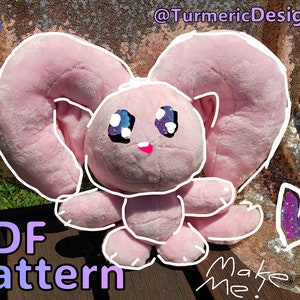 May include: A pink plush toy with large, floppy ears and cartoon-style eyes. The text "PDF Pattern" and "Make Me!" are visible. The background is a sparkly gold fabric.