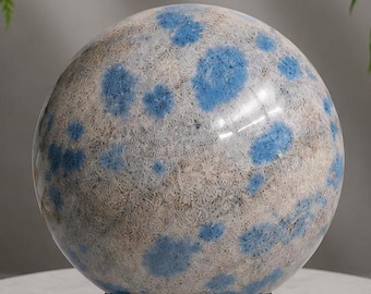 May include: A large, spherical decorative object with a speckled, light gray and white surface, punctuated by irregular blue spots. The sphere sits on a black, ornate stand, creating a striking contrast. The overall aesthetic is natural and artistic.