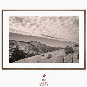 Puede incluir: Una fotografía en blanco y negro de una cordillera con un cielo nublado. La cordillera está cubierta de nieve y el cielo está lleno de nubes esponjosas. La foto fue tomada desde un punto de vista elevado, mirando hacia abajo la cordillera.
