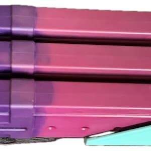 May include: A purple and pink multi-pack of magazine holders with a teal plastic handle. The handle has a snowflake design and the words "Snowflake" printed on it.