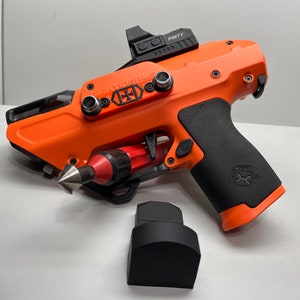 May include: An orange and black pistol with a black grip and a red and black screwdriver attached to the side. The pistol has a black sight on top and the text "NIGHTMARE" is printed on the side.
