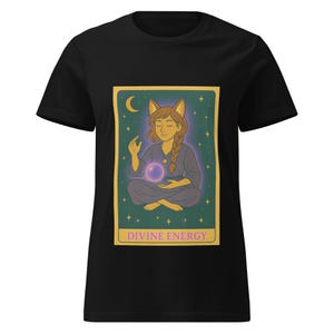 Puede incluir: Camiseta negra con un gráfico de una carta de tarot que presenta a una mujer con orejas de gato meditando con un orbe brillante. La carta se titula "Divine Energy".