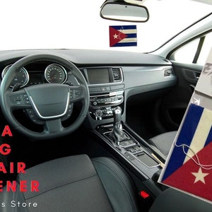 Puede incluir: Un ambientador de coche con la bandera de Cuba. El ambientador está colgado del espejo retrovisor de un coche. El texto "Cuba Flag Car Air Freshener" es visible en la imagen. El texto "Expo Designs Store" también es visible en la imagen.