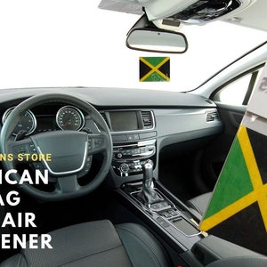 May include: A car air freshener featuring the Jamaican flag. The air freshener is hanging from the rear view mirror of a car. The text "EXPO DESIGNS STORE" and "JAMAICAN FLAG CAR AIR FRESHENER" is visible in the image.