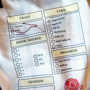 Pode incluir: Saco de tecido branco para projetos de tric&ocirc; com uma lista de verifica&ccedil;&atilde;o para trabalhos de agulha. A lista de verifica&ccedil;&atilde;o inclui se&ccedil;&otilde;es para o tipo de trabalho, o tamanho da agulha/croch&ecirc;, o peso do fio, a tens&atilde;o e o progresso. A bolsa tem um gr&aacute;fico de novelo de l&atilde; vermelho.