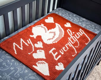 May include: A crocheted baby blanket in orange and white with the text "My Everything" and a white crocheted duck design.