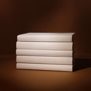 May include: A stack of five hardcover books with off-white covers. The books are neatly arranged, with the spines facing the viewer. The background is a gradient of brown hues, creating a warm, inviting atmosphere.