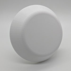 May include: A white ceramic bowl with a smooth, rounded surface. The bowl is empty and appears to be made of a thick, durable material.
