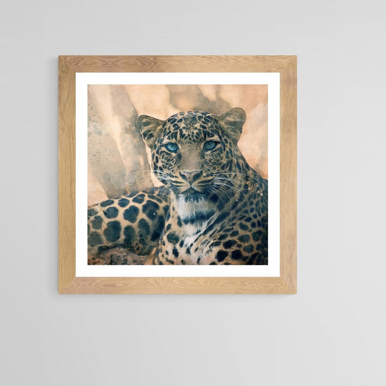 Op de afbeelding: Een aquarel schilderij van een luipaard met blauwe ogen. De luipaard ligt neer en kijkt recht naar de kijker. De achtergrond is een zachte, gedempte bruine kleur.