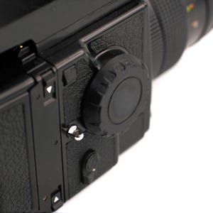 Puede incluir: Primer plano de una cámara negra con un cuerpo texturizado y una gran perilla negra en el lateral.