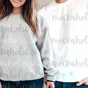 Op de afbeelding: Twee longsleeve sweatshirts, &eacute;&eacute;n grijs en &eacute;&eacute;n wit. Beide sweatshirts hebben een ronde hals en zijn gemaakt van een zachte, comfortabele stof.