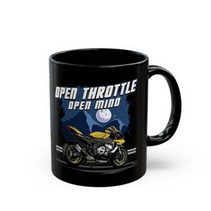 Könnte beinhalten: Schwarze Keramik-Tasse mit einem gelb-schwarzen Motorrad-Motiv und dem Text "OPEN THROTTLE OPEN MIND". Das Design beinhaltet einen Nachthimmel mit Mond. Die Tasse hat einen gebogenen Griff.