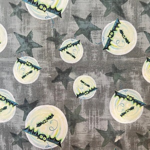 May include: A gray fabric with a repeating pattern of white moons with bats flying around them. The bats are black with green eyes and are flying in a circle around the moon. There are also gray stars scattered throughout the fabric.