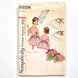 May include: Simplicity sewing pattern 5228 for a Christmas apron. The pattern includes three different apron designs: one with a gingham pattern, one with the word "Mother" embroidered on it, and one with the word "Daughter" embroidered on it. The pattern is suitable for 1" gingham only.