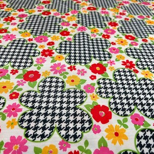 May include: White fabric with a repeating pattern of black and white houndstooth flowers with pink, red, and yellow accents.