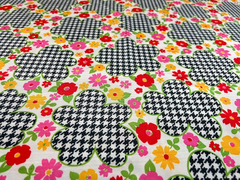 May include: White fabric with a repeating pattern of black and white houndstooth flowers with pink, red, and yellow accents.